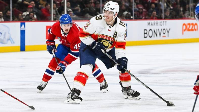 Mar 30, 2023; Montreal, Quebec, CAN; Florida Panthers left wing Matthew Tkachuk (19) plays the puck against Montreal Canadiens left wing Rafael Harvey-Pinard (49) during the third period at Bell Centre. Mandatory Credit: David Kirouac-USA TODAY Sports