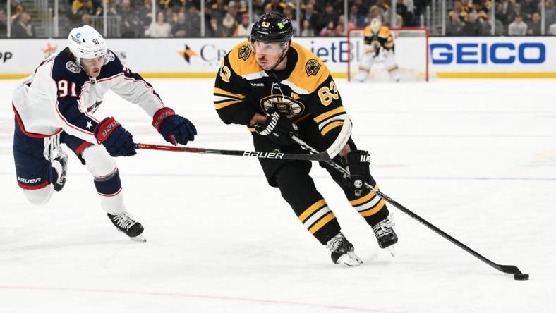 Mar 30, 2023; Boston, Massachusetts, USA; Boston Bruins left wing Brad Marchand (63) skates with the puck against Columbus Blue Jackets center Kent Johnson (91) during the third period at the TD Garden. Mandatory Credit: Brian Fluharty-USA TODAY Sports