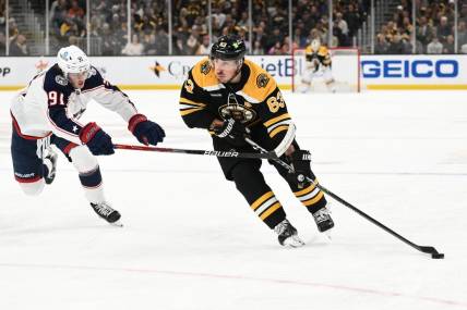 Mar 30, 2023; Boston, Massachusetts, USA; Boston Bruins left wing Brad Marchand (63) skates with the puck against Columbus Blue Jackets center Kent Johnson (91) during the third period at the TD Garden. Mandatory Credit: Brian Fluharty-USA TODAY Sports