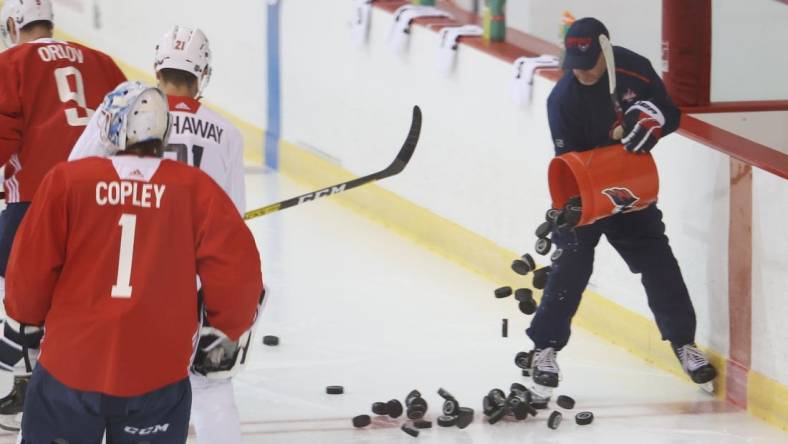 Jul 15, 2020; Arlington, Virginia, USA; Washington Capitals assistant coach Blaine Forsythe dumps pucks onto the ice during an NHL workout at MedStar Capitals Iceplex. Mandatory Credit: Geoff Burke-USA TODAY Sports