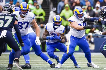 Jan 8, 2023; Seattle, Washington, USA; Los Angeles Rams running back Cam Akers (3) rushes against the Seattle Seahawks behind blocks from offensive tackle Chandler Brewer (67) and center Matt Skura (64) during the third quarter at Lumen Field. Mandatory Credit: Joe Nicholson-USA TODAY Sports