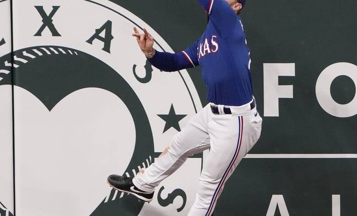 Mar 28, 2023; Arlington, Texas, USA; Texas Rangers left fielder Clint Frazier (77) leaps but is unable to catch the triple hit by Kansas City Royals senior director of hitting performance, major league hitting coach Alec Zumwalt (31) during the eighth inning of an exhibition game at Globe Life Field. Mandatory Credit: Jim Cowsert-USA TODAY Sports