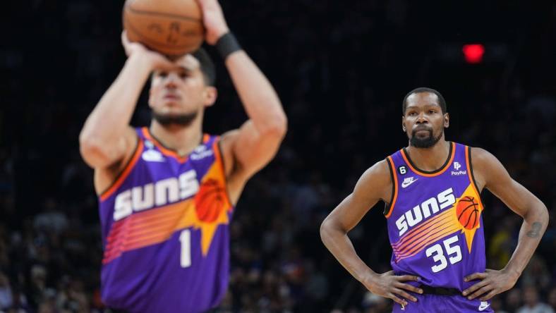 Mar 31, 2023; Phoenix, Arizona, USA; Phoenix Suns forward Kevin Durant (35) watches as Phoenix Suns guard Devin Booker (1) shoots a free throw against the Denver Nuggets during the first half at Footprint Center. Mandatory Credit: Joe Camporeale-USA TODAY Sports