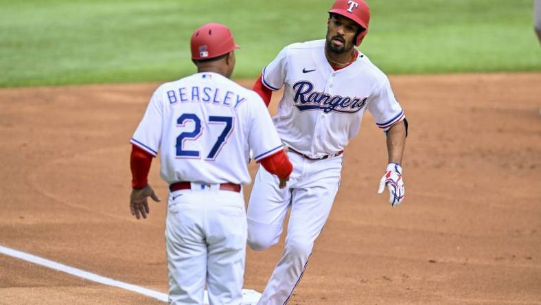 Apr 1, 2023; Arlington, Texas, USA; Texas Rangers second baseman Marcus Semien (2) rounds third base past third base coach Tony Beasley (27) after Semien hits a lead off home run against the Philadelphia Phillies during the first inning at Globe Life Field. Mandatory Credit: Jerome Miron-USA TODAY Sports