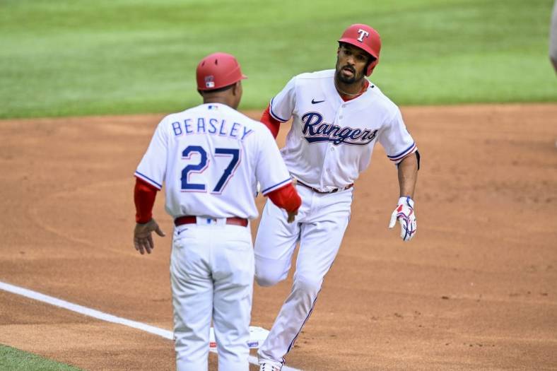 Apr 1, 2023; Arlington, Texas, USA; Texas Rangers second baseman Marcus Semien (2) rounds third base past third base coach Tony Beasley (27) after Semien hits a lead off home run against the Philadelphia Phillies during the first inning at Globe Life Field. Mandatory Credit: Jerome Miron-USA TODAY Sports