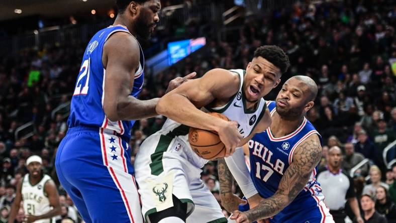 Apr 2, 2023; Milwaukee, Wisconsin, USA; Milwaukee Bucks forward Giannis Antetokounmpo (34) fights for the ball against Philadelphia 76ers forward P.J. Tucker (17) and forward Joel Embiid (21) during the first quarter at Fiserv Forum. Mandatory Credit: Benny Sieu-USA TODAY Sports