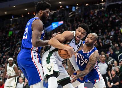 Apr 2, 2023; Milwaukee, Wisconsin, USA; Milwaukee Bucks forward Giannis Antetokounmpo (34) fights for the ball against Philadelphia 76ers forward P.J. Tucker (17) and forward Joel Embiid (21) during the first quarter at Fiserv Forum. Mandatory Credit: Benny Sieu-USA TODAY Sports