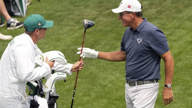 Apr 7, 2023; Augusta, Georgia, USA; Phil Mickelson hands his driver to caddie Tim Mickelson on the 18th tee box during the second round of The Masters golf tournament. Mandatory Credit: Michael Madrid-USA TODAY Network