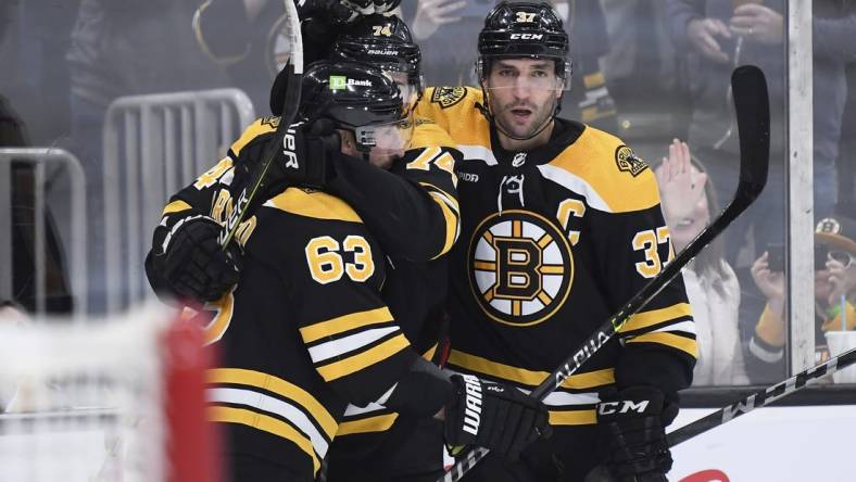 Apr 11, 2023; Boston, Massachusetts, USA; Boston Bruins left wing Brad Marchand (63) and center Patrice Bergeron (37) congratulate left wing Jake DeBrusk (74) after scoring a goal during the third period against the Washington Capitals at TD Garden. Mandatory Credit: Bob DeChiara-USA TODAY Sports