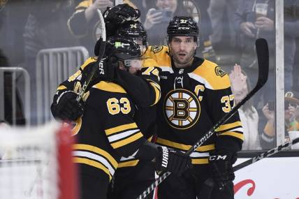 Apr 11, 2023; Boston, Massachusetts, USA; Boston Bruins left wing Brad Marchand (63) and center Patrice Bergeron (37) congratulate left wing Jake DeBrusk (74) after scoring a goal during the third period against the Washington Capitals at TD Garden. Mandatory Credit: Bob DeChiara-USA TODAY Sports