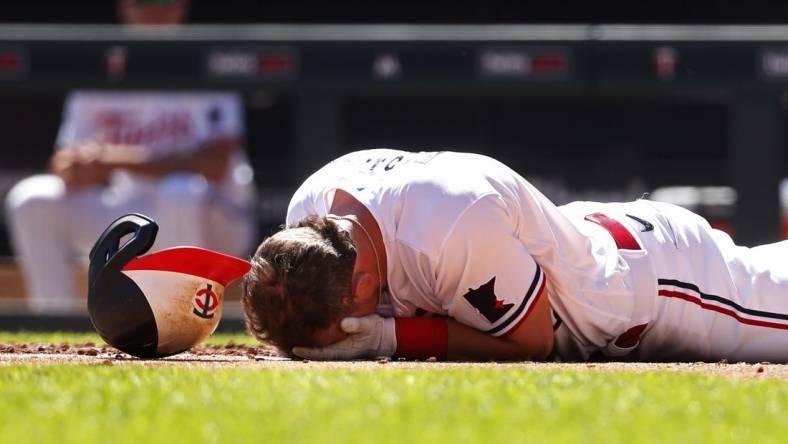 Apr 12, 2023; Minneapolis, Minnesota, USA; Minnesota Twins second baseman Kyle Farmer (12) drops to the ground after getting hit by a pitch in the face by the Chicago White Sox in the fourth inning at Target Field. Mandatory Credit: Bruce Kluckhohn-USA TODAY Sports