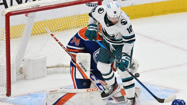 Apr 13, 2023; Edmonton, Alberta, CAN;   Edmonton Oilers goalie Stuart Skinner (74) battles for the puck with  San Jose Sharks left winger Evgeny Svechnikov (10) during the first period at Rogers Place. Mandatory Credit: Walter Tychnowicz-USA TODAY Sports