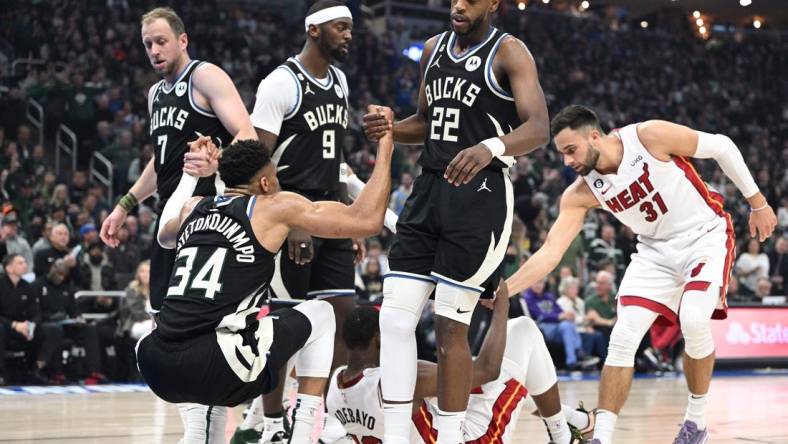 Apr 16, 2023; Milwaukee, Wisconsin, USA; Milwaukee Bucks forward Giannis Antetokounmpo (34) is helped up after a collision in the first half against Miami Heat center Bam Adebayo (13) during game one of the 2023 NBA Playoffs at Fiserv Forum. Mandatory Credit: Michael McLoone-USA TODAY Sports