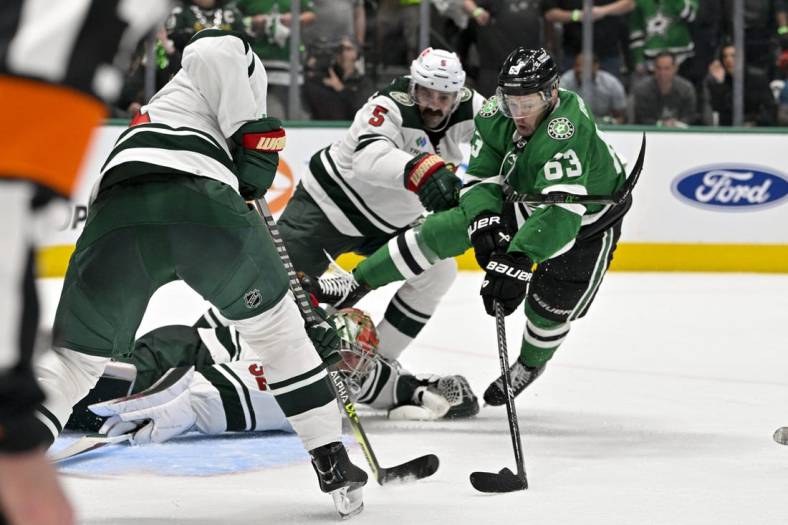 Apr 17, 2023; Dallas, Texas, USA; Minnesota Wild defenseman Jake Middleton (5) checks Dallas Stars right wing Evgenii Dadonov (63) as he attempts to poke the puck past goaltender Filip Gustavsson (32) during the first overtime period in game one of the first round of the 2023 Stanley Cup Playoffs at the American Airlines Center. Mandatory Credit: Jerome Miron-USA TODAY Sports