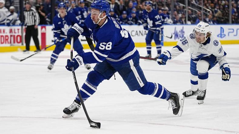 Apr 18, 2023; Toronto, Ontario, CAN; Toronto Maple Leafs forward Michael Bunting (58) shoots the puck as Tampa Bay Lightning forward Brandon Hagel (38) closes in during the first period of game one of the first round of the 2023 Stanley Cup Playoffs at Scotiabank Arena. Mandatory Credit: John E. Sokolowski-USA TODAY Sports