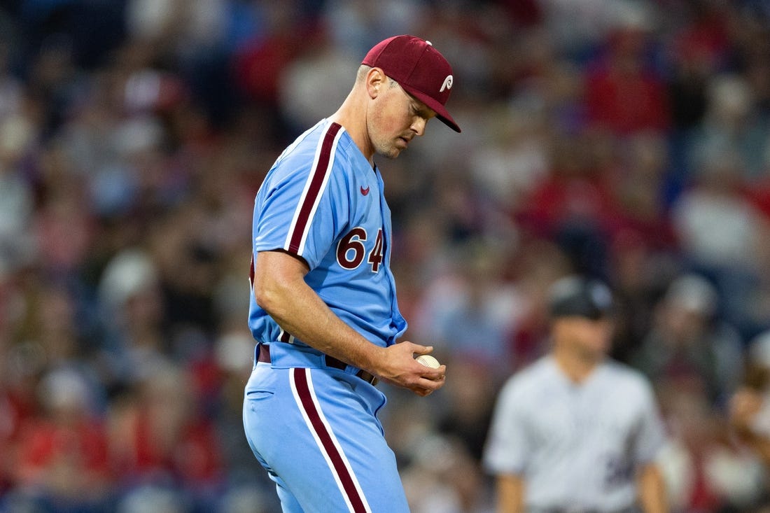 Apr 20, 2023; Philadelphia, Pennsylvania, USA; Philadelphia Phillies relief pitcher Andrew Bellatti (64) looks at the ball after walking in a run during the sixth inning against the Colorado Rockies at Citizens Bank Park. Mandatory Credit: Bill Streicher-USA TODAY Sports