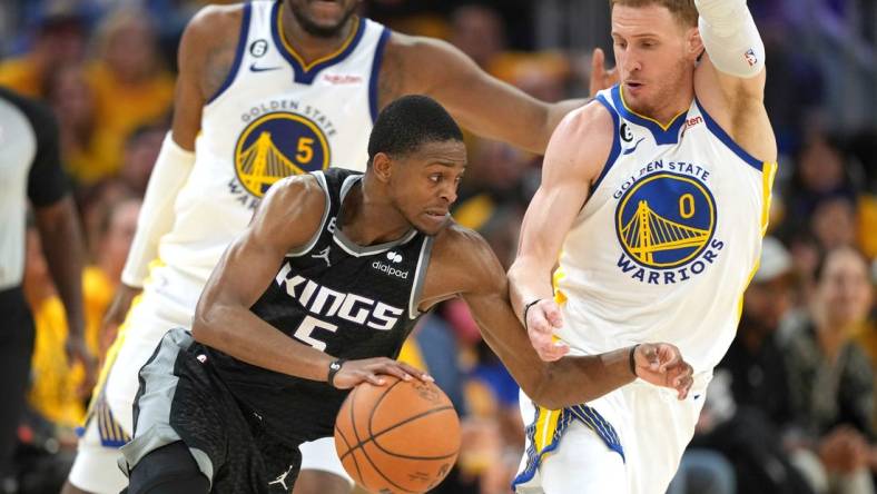 Apr 23, 2023; San Francisco, California, USA; Sacramento Kings guard Malik Monk (0) dribbles against Golden State Warriors guard Donte DiVincenzo (0) during the third quarter of game four of the 2023 NBA playoffs at Chase Center. Mandatory Credit: Darren Yamashita-USA TODAY Sports