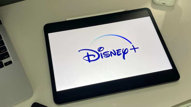 iPad with disney plus logo sitting on a desk next to a laptop