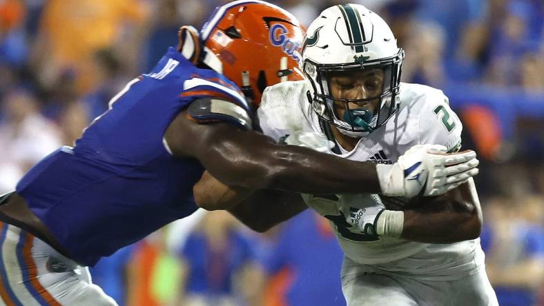 Sep 17, 2022; Gainesville, Florida, USA; South Florida Bulls running back Michel Dukes (2) runs with the ball as Florida Gators linebacker Brenton Cox Jr. (1) defends during the second half at Ben Hill Griffin Stadium. Mandatory Credit: Kim Klement-USA TODAY Sports