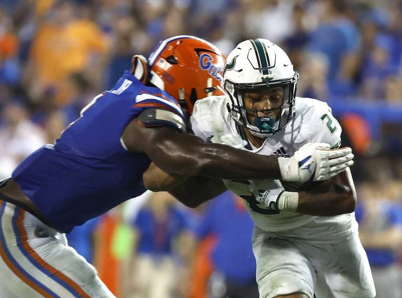 Sep 17, 2022; Gainesville, Florida, USA; South Florida Bulls running back Michel Dukes (2) runs with the ball as Florida Gators linebacker Brenton Cox Jr. (1) defends during the second half at Ben Hill Griffin Stadium. Mandatory Credit: Kim Klement-USA TODAY Sports