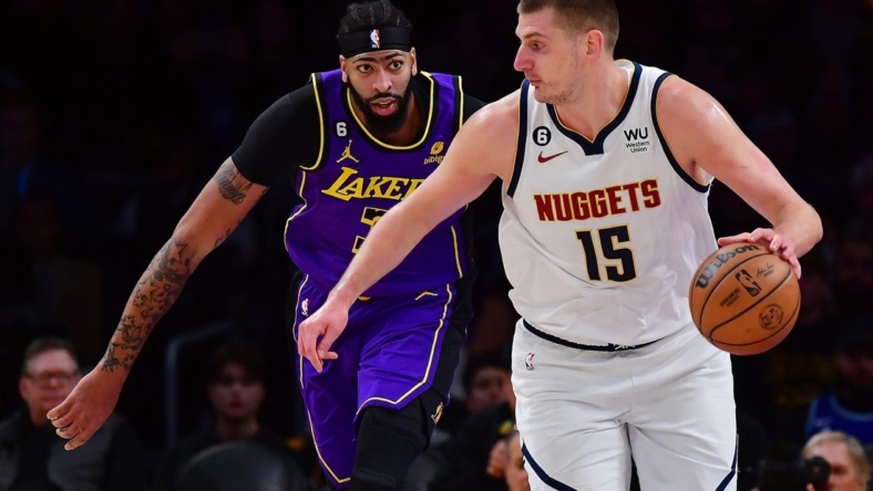 Dec 16, 2022; Los Angeles, California, USA; Denver Nuggets center Nikola Jokic (15) moves the ball ahead of Los Angeles Lakers forward Anthony Davis (3)  during the first half at Crypto.com Arena. Mandatory Credit: Gary A. Vasquez-USA TODAY Sports