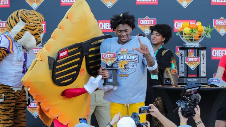 Jan 2, 2023; Orlando, FL, USA; LSU Tigers wide receiver Malik Nabers (8) is presented with most valuable player trophy by Cheez-it mascot after the game against the Purdue Boilermakers at Camping World Stadium. Mandatory Credit: Mike Watters-USA TODAY Sports