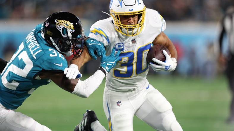 Jan 14, 2023; Jacksonville, Florida, USA; Los Angeles Chargers running back Austin Ekeler (30) is tackled by Jacksonville Jaguars cornerback Tyson Campbell (32) during the first quarter of a wild card game at TIAA Bank Field. Mandatory Credit: Nathan Ray Seebeck-USA TODAY Sports