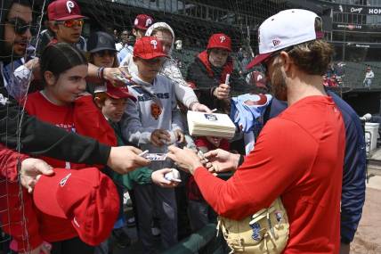 Apr 19, 2023; Chicago, Illinois, USA;   Philadelphia Phillies  Bryce Harper (right) signs autographs for young fans in the stands prior to the game against the Chicago White Sox at Guaranteed Rate Field. Mandatory Credit: Matt Marton-USA TODAY Sports
