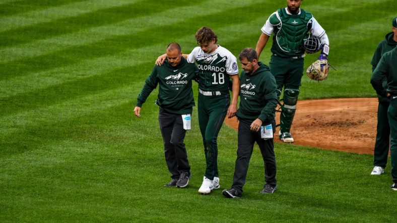 May 13, 2023; Denver, Colorado, USA; Colorado Rockies starting pitcher Ryan Feltner (18) is helped off the field by the medical staff after getting hit by a line drive by Philadelphia Phillies Nick Castellanos in the second inning at Coors Field. Mandatory Credit: John Leyba-USA TODAY Sports