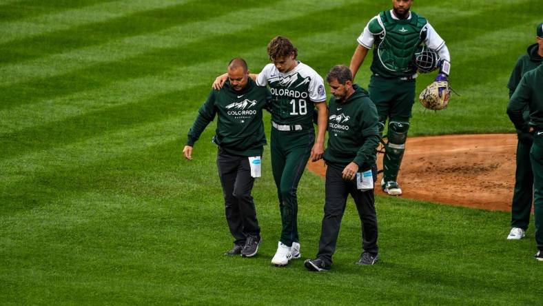 May 13, 2023; Denver, Colorado, USA; Colorado Rockies starting pitcher Ryan Feltner (18) is helped off the field by the medical staff after getting hit by a line drive by Philadelphia Phillies Nick Castellanos in the second inning at Coors Field. Mandatory Credit: John Leyba-USA TODAY Sports