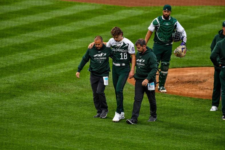 May 13, 2023; Denver, Colorado, USA; Colorado Rockies starting pitcher Ryan Feltner (18) is helped off the field by the medical staff after getting hit by a line drive by Philadelphia Phillies Nick Castellanos in the second inning at Coors Field. Mandatory Credit: John Leyba-USA TODAY Sports