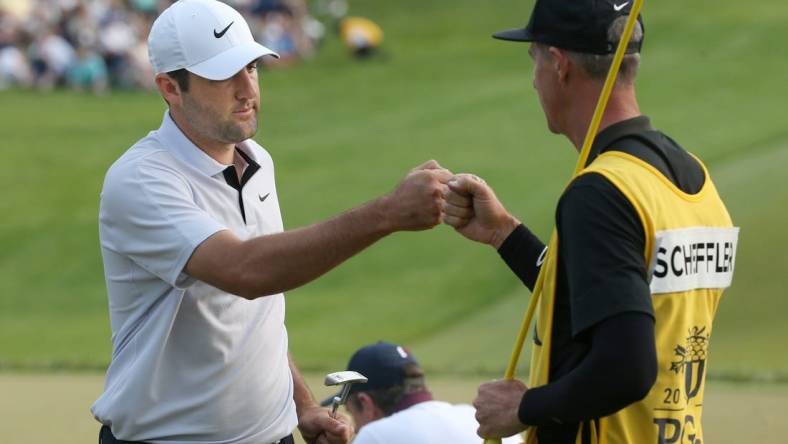 Scottie Scheffler fist-bumps his caddie Ted Scott after his final putt at the 18th hole during the final round at the PGA Championship at Oak Hill Country Club Sunday, May 21, 2023.