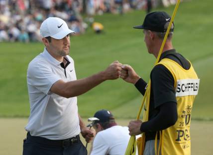 Scottie Scheffler fist-bumps his caddie Ted Scott after his final putt at the 18th hole during the final round at the PGA Championship at Oak Hill Country Club Sunday, May 21, 2023.