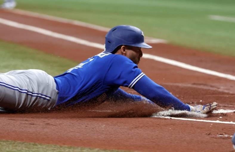 May 23, 2023; St. Petersburg, Florida, USA; Toronto Blue Jays right fielder George Springer (4) slides home to score a run  against the Tampa Bay Rays during the first inning at Tropicana Field. Mandatory Credit: Kim Klement-USA TODAY Sports