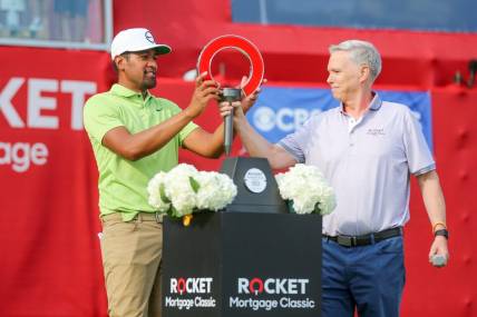 Tony Finau receives the 2022 Rocket Mortgage Classic trophy in joy after winning at the Detroit Golf Club last year. 

Rocket Mortgage Classic