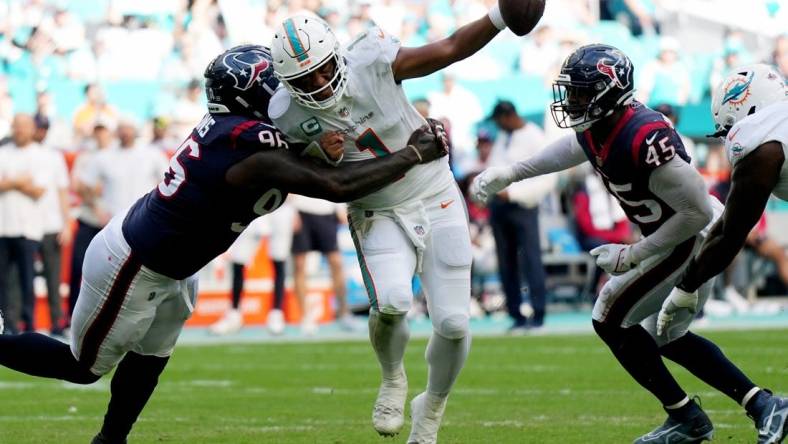 Miami Dolphins quarterback Tua Tagovailoa (1) gets his by Houston Texans defensive tackle Maliek Collins (96) as linebacker Ogbonnia Okoronkwo (45) closes in during the first half of an NFL game at Hard Rock Stadium in Miami Gardens, Nov. 27, 2022.