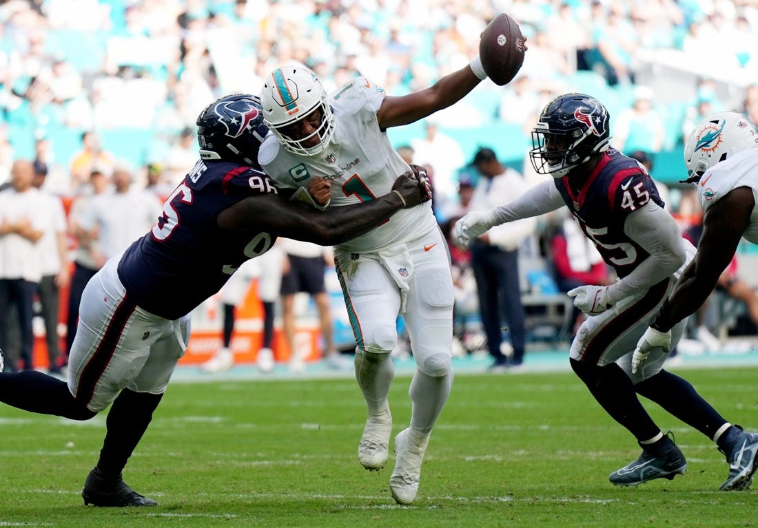 Miami Dolphins quarterback Tua Tagovailoa (1) gets his by Houston Texans defensive tackle Maliek Collins (96) as linebacker Ogbonnia Okoronkwo (45) closes in during the first half of an NFL game at Hard Rock Stadium in Miami Gardens, Nov. 27, 2022.