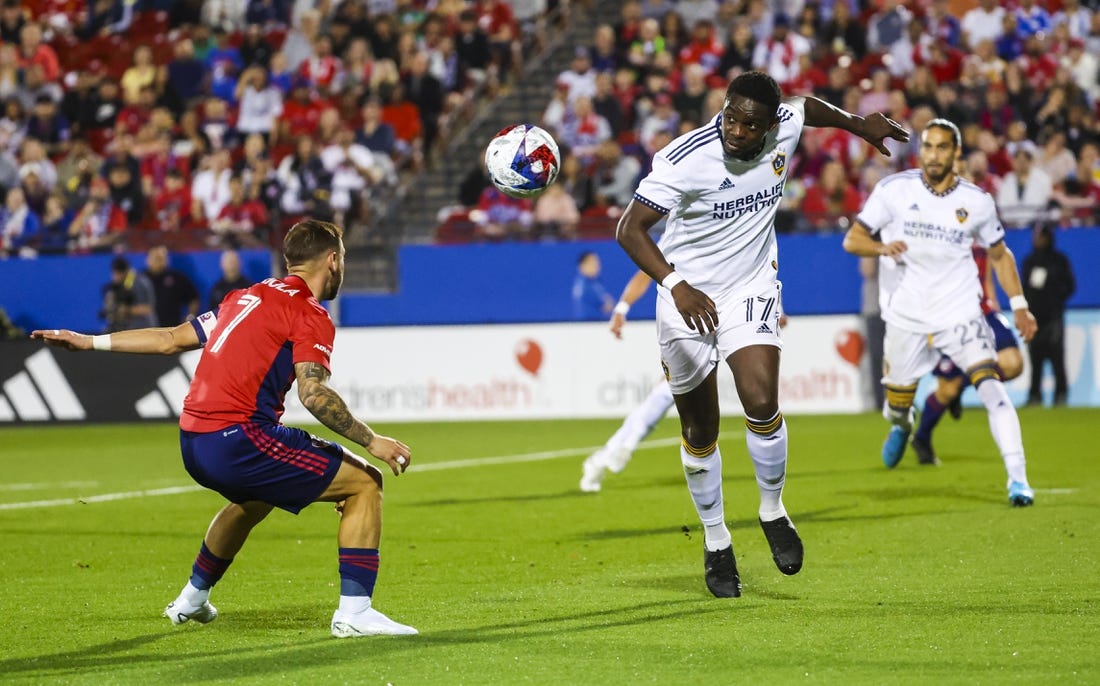 Mar 4, 2023; Frisco, Texas, USA;  Los Angeles Galaxy midfielder Chris Mavinga (17) heads teh ball past FC Dallas forward Paul Arriola (7) during the first half at Toyota Stadium. Mandatory Credit: Kevin Jairaj-USA TODAY Sports