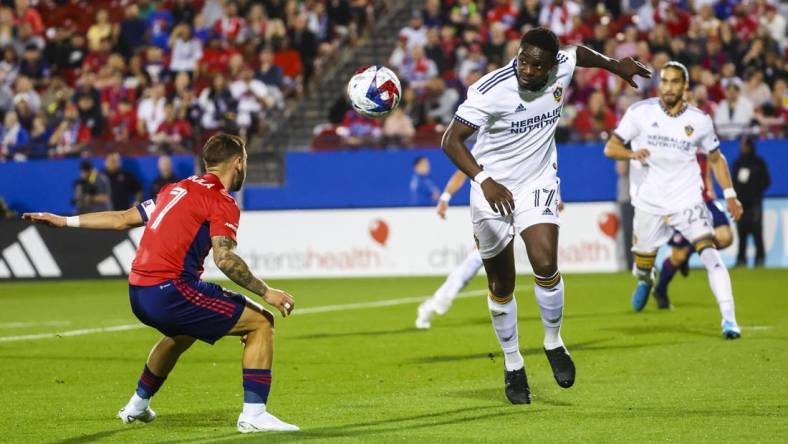 Mar 4, 2023; Frisco, Texas, USA;  Los Angeles Galaxy midfielder Chris Mavinga (17) heads teh ball past FC Dallas forward Paul Arriola (7) during the first half at Toyota Stadium. Mandatory Credit: Kevin Jairaj-USA TODAY Sports