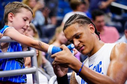 Apr 2, 2023; Orlando, Florida, USA;  Orlando Magic forward Paolo Banchero (5) signs a fans cast prior to a game against the Detroit Pistons at Amway Center. Mandatory Credit: Rich Storry-USA TODAY Sports