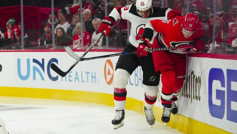 May 3, 2023; Raleigh, North Carolina, USA; New Jersey Devils defenseman Ryan Graves (33) checks Carolina Hurricanes right wing Jesse Puljujarvi (13) during the third period in game one of the second round of the 2023 Stanley Cup Playoffs at PNC Arena. Mandatory Credit: James Guillory-USA TODAY Sports