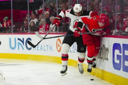 May 3, 2023; Raleigh, North Carolina, USA; New Jersey Devils defenseman Ryan Graves (33) checks Carolina Hurricanes right wing Jesse Puljujarvi (13) during the third period in game one of the second round of the 2023 Stanley Cup Playoffs at PNC Arena. Mandatory Credit: James Guillory-USA TODAY Sports