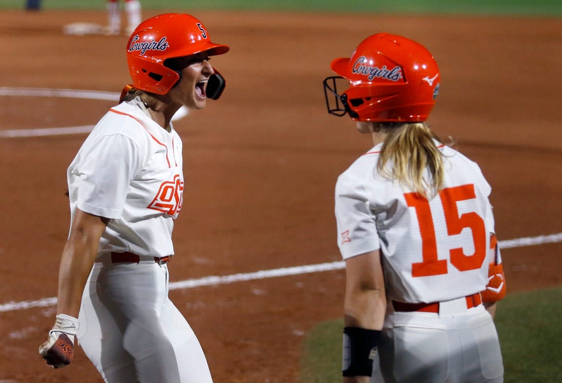 Oklahoma State's Kiley Naomi (5) celebrates a score with Rachel Becker (15) in the first inning during a softball game between Oklahoma State and Utah in the Women's College World Series at USA Softball Hall of Fame Stadium in  in Oklahoma City, Friday, June, 2, 2023.