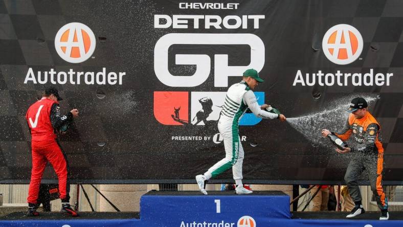 Detroit Grand Prix winner Alex Palou, center, second place Will Power, left, and third place Felix Rosenqvist celebrate their top three finish with champagne in Detroit on Sunday, June 4, 2023.