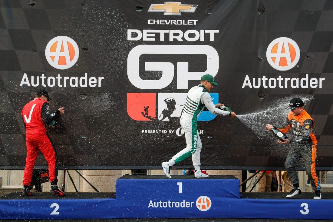 Detroit Grand Prix winner Alex Palou, center, second place Will Power, left, and third place Felix Rosenqvist celebrate their top three finish with champagne in Detroit on Sunday, June 4, 2023.