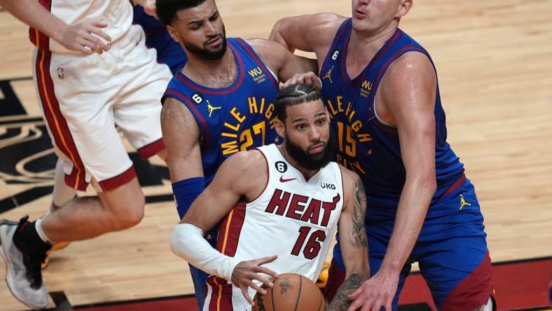 Jun 7, 2023; Miami, Florida, USA; Miami Heat forward Caleb Martin (16) attempts to dribble the ball against Denver Nuggets guard Jamal Murray (27) and center Nikola Jokic (15) during the first quarter in game three of the 2023 NBA Finals at Kaseya Center. Mandatory Credit: Jim Rassol-USA TODAY Sports