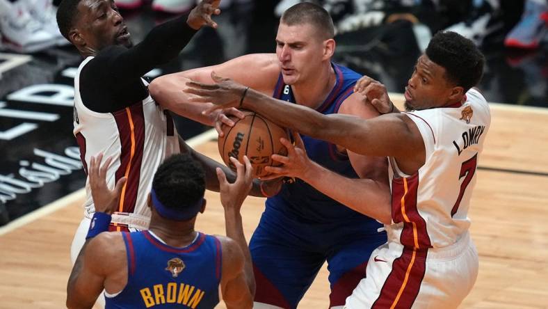 Jun 7, 2023; Miami, Florida, USA; Denver Nuggets center Nikola Jokic (15) grabs a rebound over Miami Heat guard Kyle Lowry (7) and center Bam Adebayo (13) during the second quarter in game three of the 2023 NBA Finals at Kaseya Center. Mandatory Credit: Jim Rassol-USA TODAY Sports