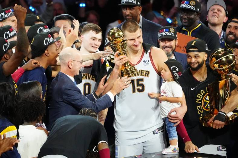 Jun 12, 2023; Denver, Colorado, USA; NBA commissioner Adam Silver presents the Bill Russell NBA Finals MVP Award to Denver Nuggets center Nikola Jokic (15) as Jokic holds his daughter Ognjena Jokic after the Nuggets won the 2023 NBA Championship against the Miami Heat at Ball Arena. Looking on is Denver guard Jamal Murray (27) holds the Larry O'Brien Trophy. Mandatory Credit: Ron Chenoy-USA TODAY Sports