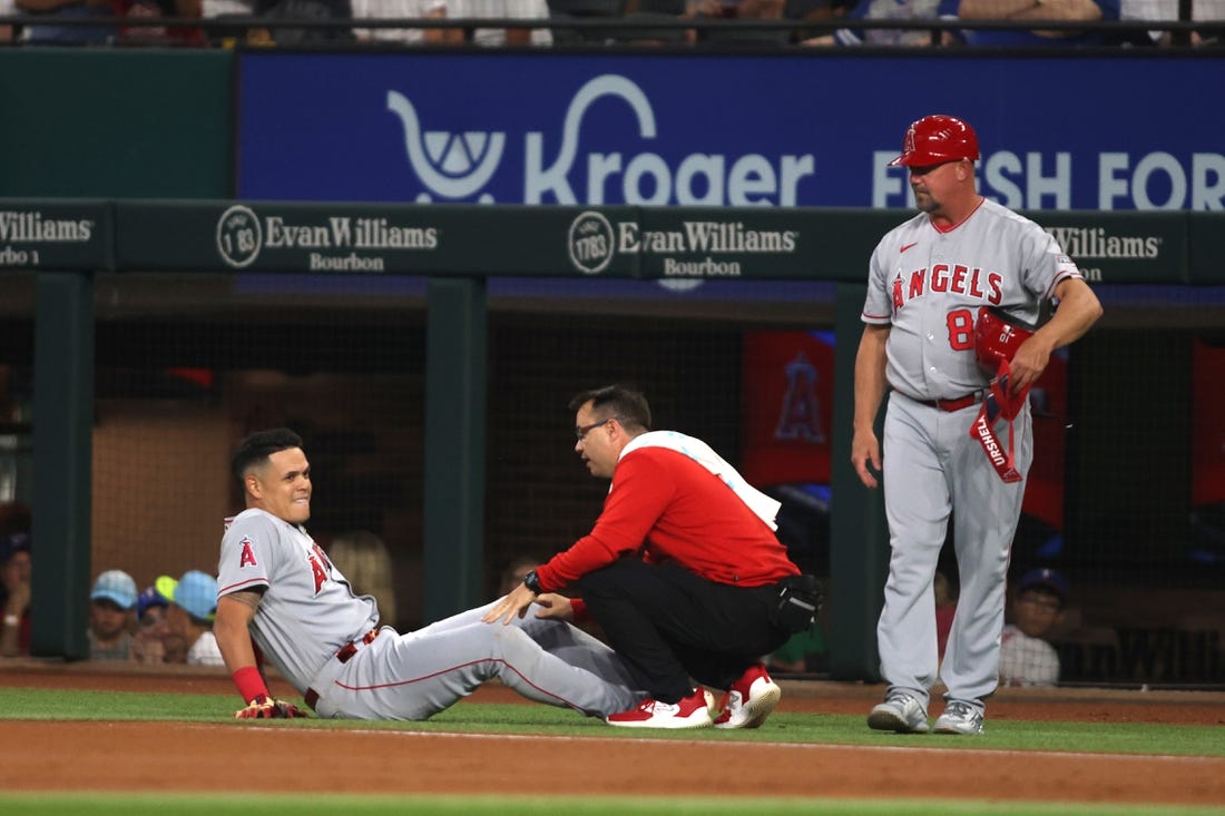 Jun 15, 2023; Arlington, Texas, USA; Los Angeles Angels third baseman Gio Urshela (10) is looked at by the trainer after injuring his knee in the first inning against the Texas Rangers at Globe Life Field. Mandatory Credit: Tim Heitman-USA TODAY Sports