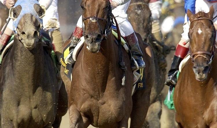 Jockey Jose Santos raised his hand in victory after he rode Funny Cide to a 1-length triumph over Empire Maker, left, in the 129th Kentucky Derby yesterday at Churchill Downs. May 3, 2003